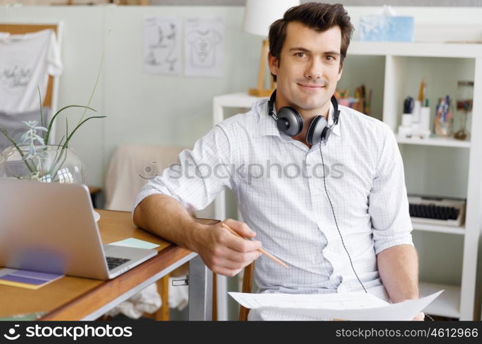 Portrait of young man wearing casual in office. Portrait of young businessman in office with headphones