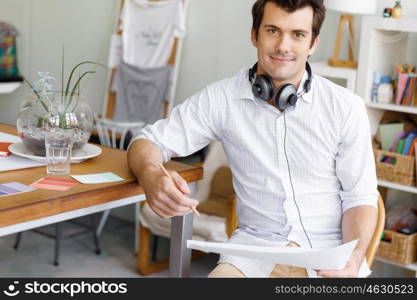 Portrait of young man wearing casual in office. Portrait of young businessman in office with headphones