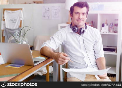 Portrait of young man wearing casual in office. Portrait of young businessman in office with headphones