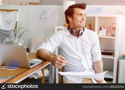 Portrait of young man wearing casual in office. Portrait of young businessman in office with headphones