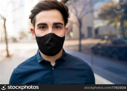 Portrait of young man wearing protective mask while standing outdoors on the street. New normal lifestyle concept.