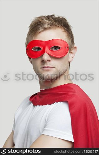 Portrait of young man wearing superhero costume against gray background