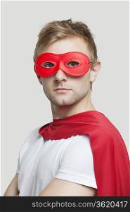 Portrait of young man wearing superhero costume against gray background