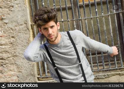 Portrait of young man wearing suspenders in urban background