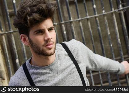 Portrait of young man wearing suspenders in urban background