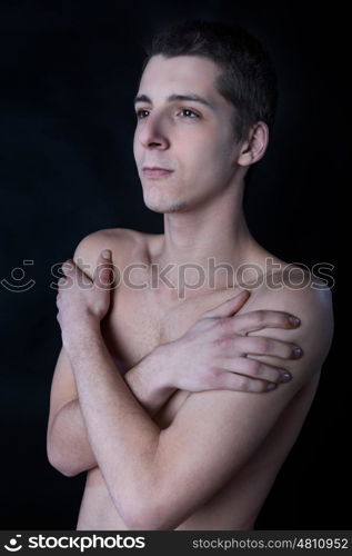 portrait of young man with arms cross against black background