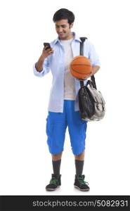 Portrait of young man with briefcase and basket ball using mobile phone