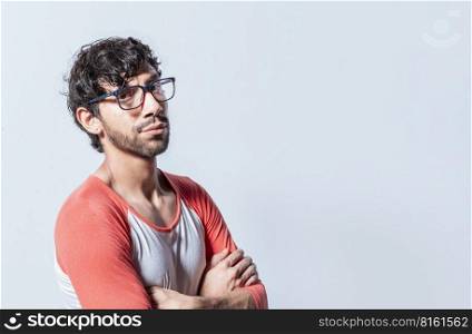 Portrait of young man with crossed arms isolated. Young latin man in glasses with crossed arms looking in profile at the camera. Nicaraguan man with crossed arms looking at the camera isolated