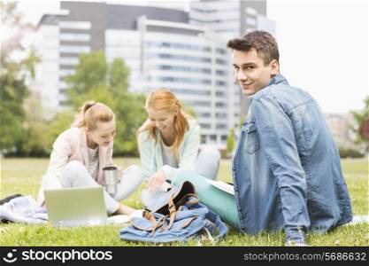 Portrait of young man with female friends studying on university campus