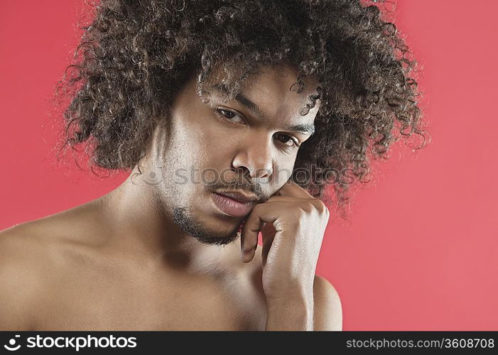 Portrait of young man with hand on chin over colored background