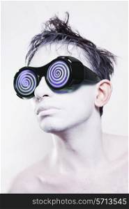 Portrait of young man with white skin in strange violet glasses on white background