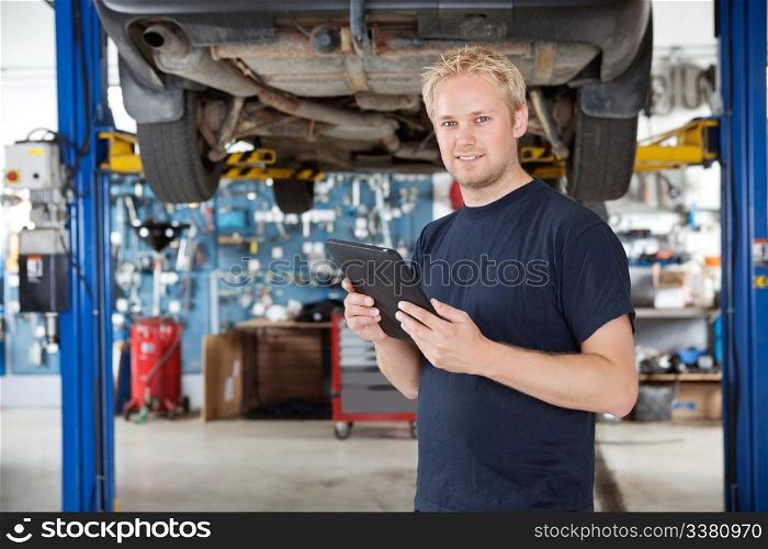 Portrait of young mechanic holding digital tablet in his auto repair shop