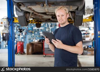 Portrait of young mechanic holding digital tablet in his auto repair shop