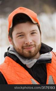 Portrait of young mid-adult male wearing blaze orange safety hunting clothing.