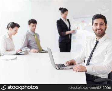 portrait of young modern arab business man with beard at office, group of business people on meeting making presentation in background