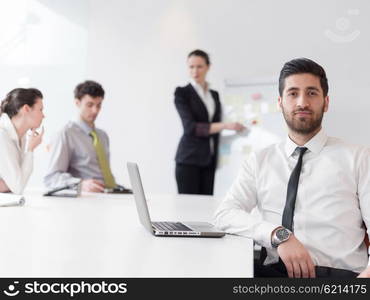 portrait of young modern arab business man with beard at office, group of business people on meeting making presentation in background