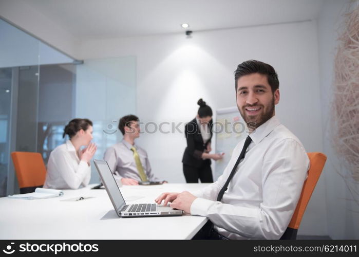 portrait of young modern arab business man with beard at office meeting room, group of business people on brainstorming and making plans and projects on white flip board in background