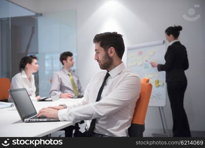 portrait of young modern arab business man with beard at office meeting room, group of business people on brainstorming and making plans and projects on white flip board in background