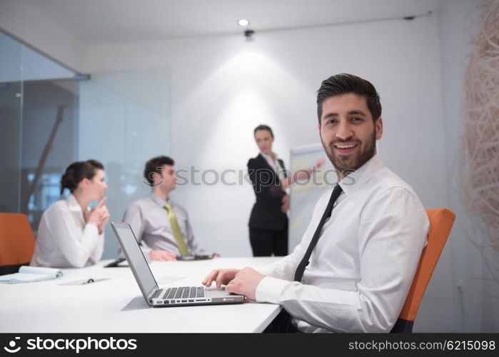 portrait of young modern arab business man with beard at office meeting room, group of business people on brainstorming and making plans and projects on white flip board in background