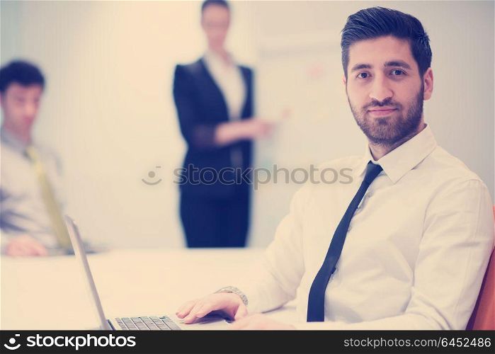 portrait of young modern arab business man with beard at office meeting room, group of business people on brainstorming and making plans and projects on white flip board in background