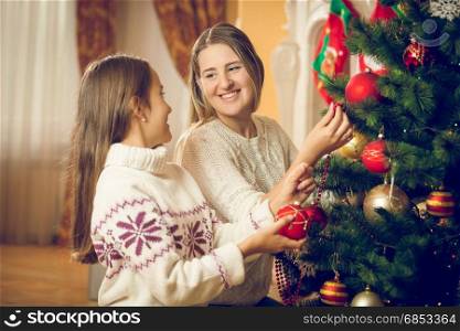 Portrait of young mother and daughter decorating Christmas tree