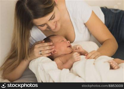 Portrait of young mother posing with baby boy on bed