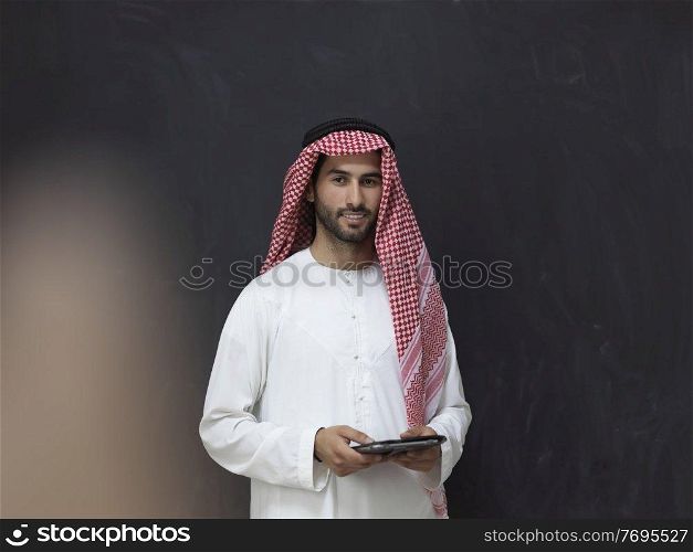 Portrait of young muslim businessman using tablet. Successful Arab boy in traditional clothes representing technology