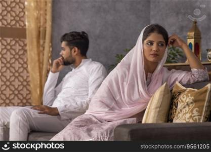 Portrait of young Muslim couple ignoring each other after an argument in living room