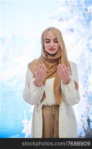 Portrait of young muslim woman praying or making dua to God. Girl with modern and fashionable clothes on winter concept background.