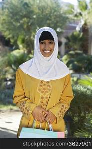 Portrait of young muslim woman with shopping bag, smiling