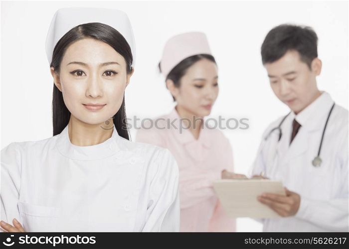 Portrait of young nurse, doctor and nurse in the background, studio shot