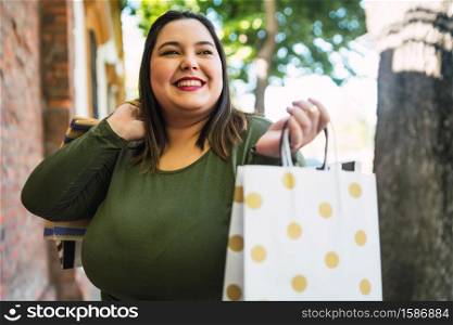 Portrait of young plus size woman holding shopping bags outdoors on the street. Shopping and sale concept.