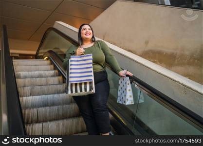 Portrait of young plus size woman holding shopping bags while doing shopping at the mall. Shopping and sale concept.