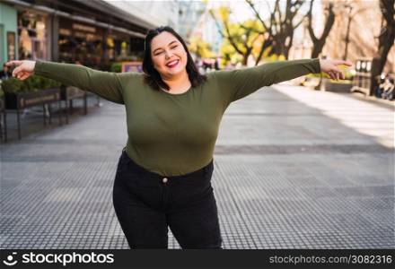 Portrait of young plus size woman smiling while standing outdoors at the street. Urban concept.