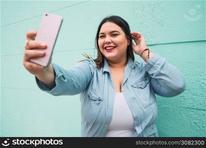 Portrait of young plus size woman taking selfies with her mophile phone outdoors. Lifestyle concept.