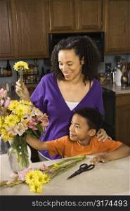 Portrait of young pregnant mother and son arranging flowers.