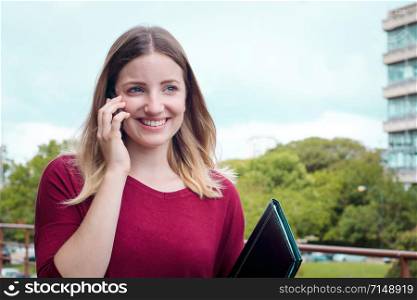 Portrait of young pretty woman talking on her mobile phone. Outdoors.