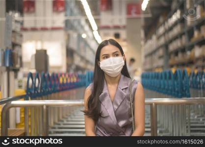 Portrait of young pretty woman wearing a surgical mask in shopping mall, covid-19 and pandemic concept.