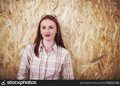 portrait of young redhead business woman with glasses isolated on a wooden background