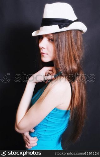 portrait of young sad girl in white hat on black background