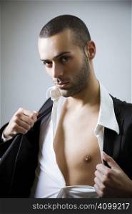 Portrait of young sexy man showing his bare chest and getting naked