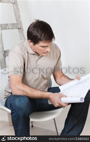 Portrait of young smart man looking at blueprint