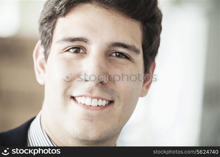 Portrait of young smiling businessman looking at camera, head and shoulders