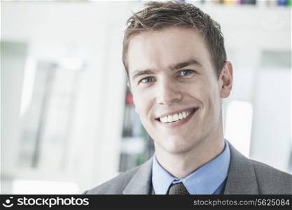 Portrait of young smiling businessman looking at camera, head and shoulders