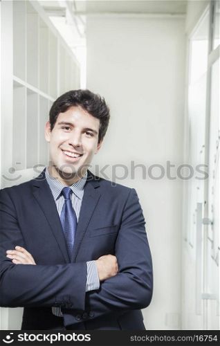 Portrait of young smiling businessman with arms crossed and looking into the camera