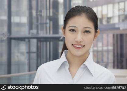 Portrait of young smiling businesswoman, building exterior in the background