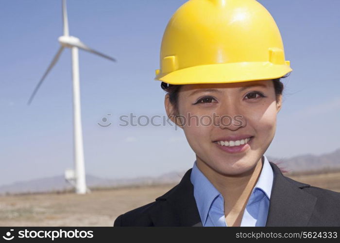 Portrait of young smiling female engineer checking wind turbines on site