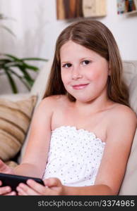 Portrait of young smiling girl looking at you in living room