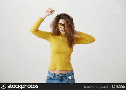 portrait of young smiling happy woman with curly hairstyle posing isolated on white studio background, listening to music in earphones, waving hair.. portrait of young smiling happy woman with curly hairstyle posing isolated on white studio background, listening to music in earphones, waving hair