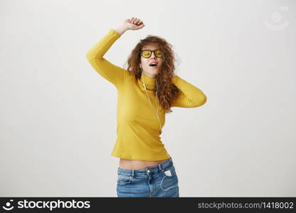 portrait of young smiling happy woman with curly hairstyle posing isolated on white studio background, listening to music in earphones, waving hair.. portrait of young smiling happy woman with curly hairstyle posing isolated on white studio background, listening to music in earphones, waving hair